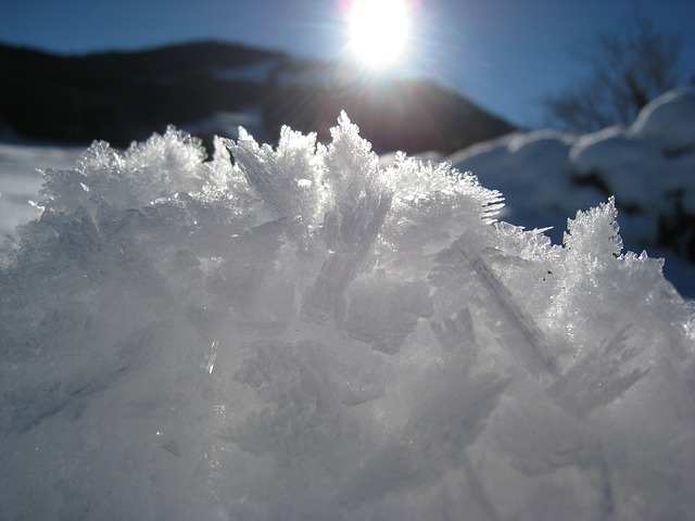 Close up photo of small snow mountain with the sun and mountains in the background. New Record for Temperature