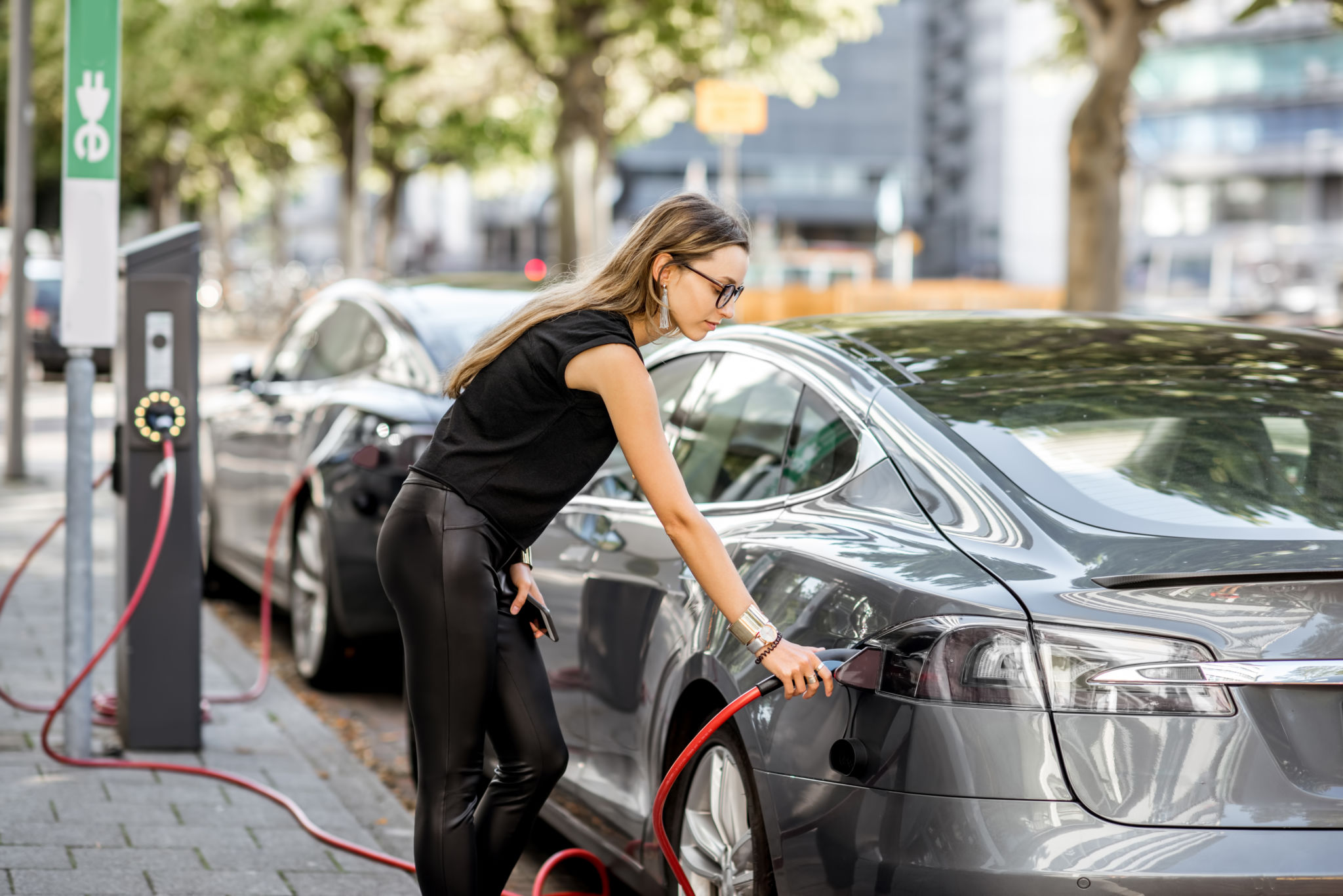 Woman charing electric cars connected to power grid