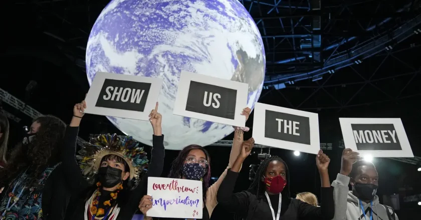 Image of people holding signs that read "show us the money" for the Climate Finance at COP27 post | Climate Nexus