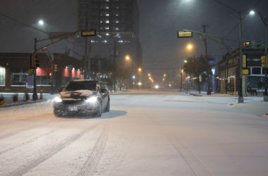 A car drives through a snowstorm at nighttime