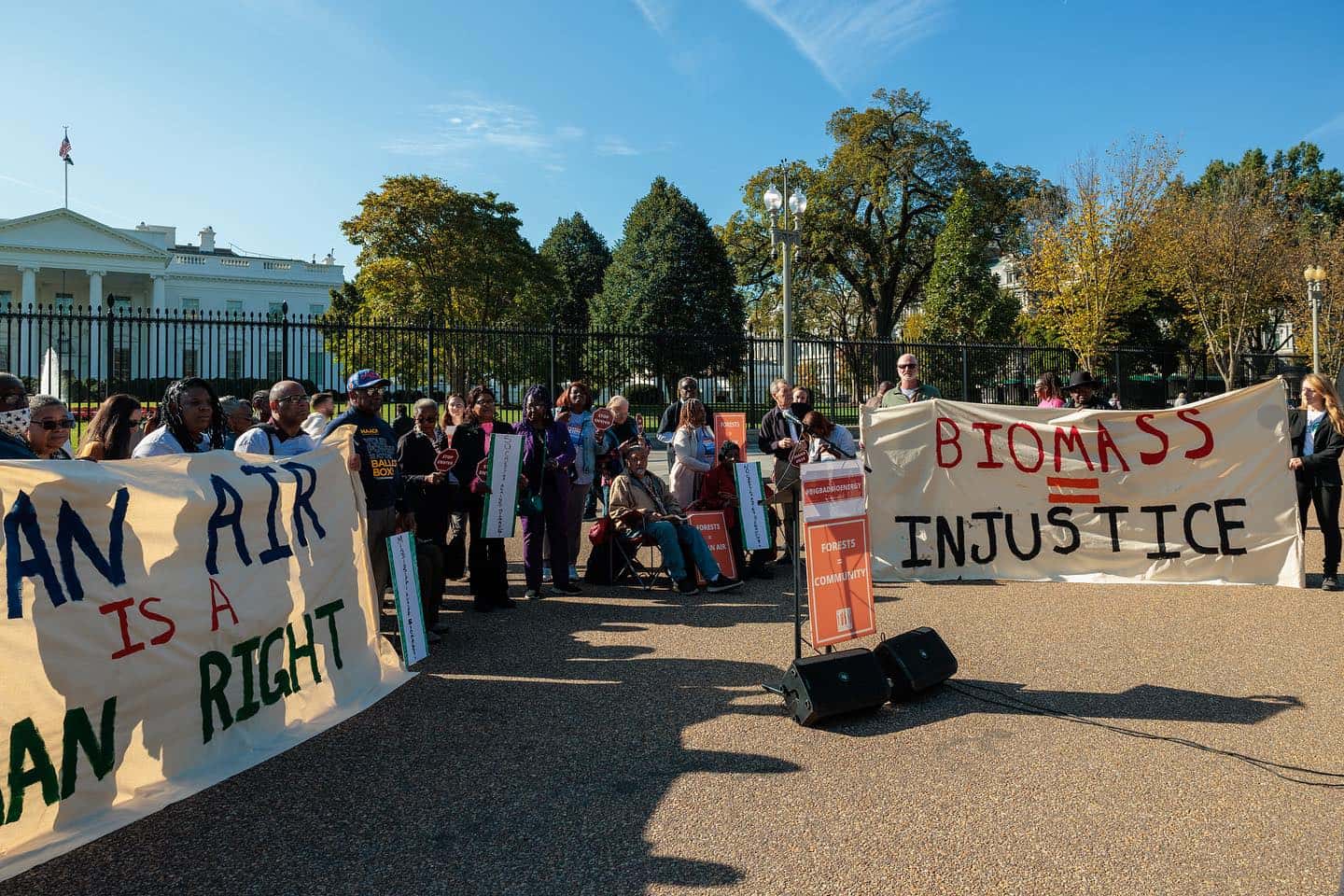 A group of protesters gathered outside of the White House, holding signs that read "Biomass is Injustice" and "Clean Air is a Human Right."
