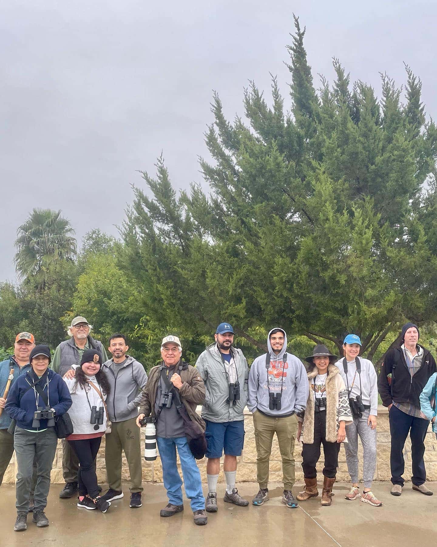 A group of people in hiking clothes stand in a rainy outdoor environment