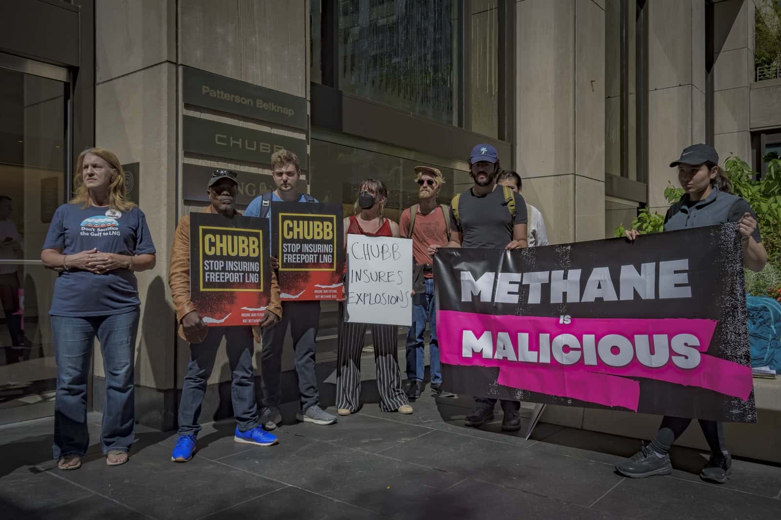 A group of people standing in a row holding protest signs that read "Methane is Malicious."