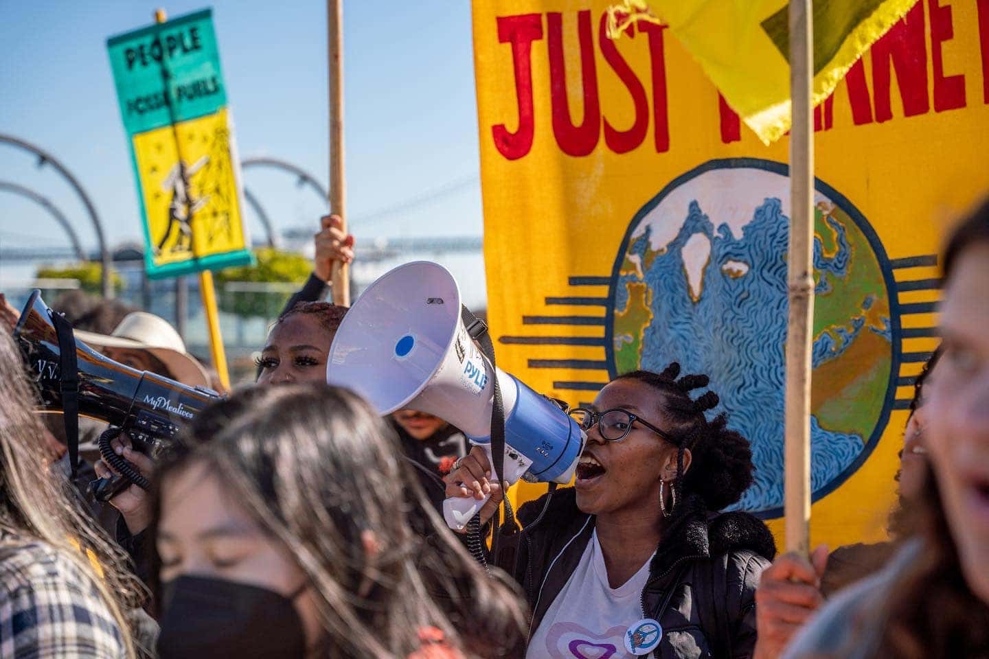 A group of young people are gathered in a public space in protest of climate injustices.